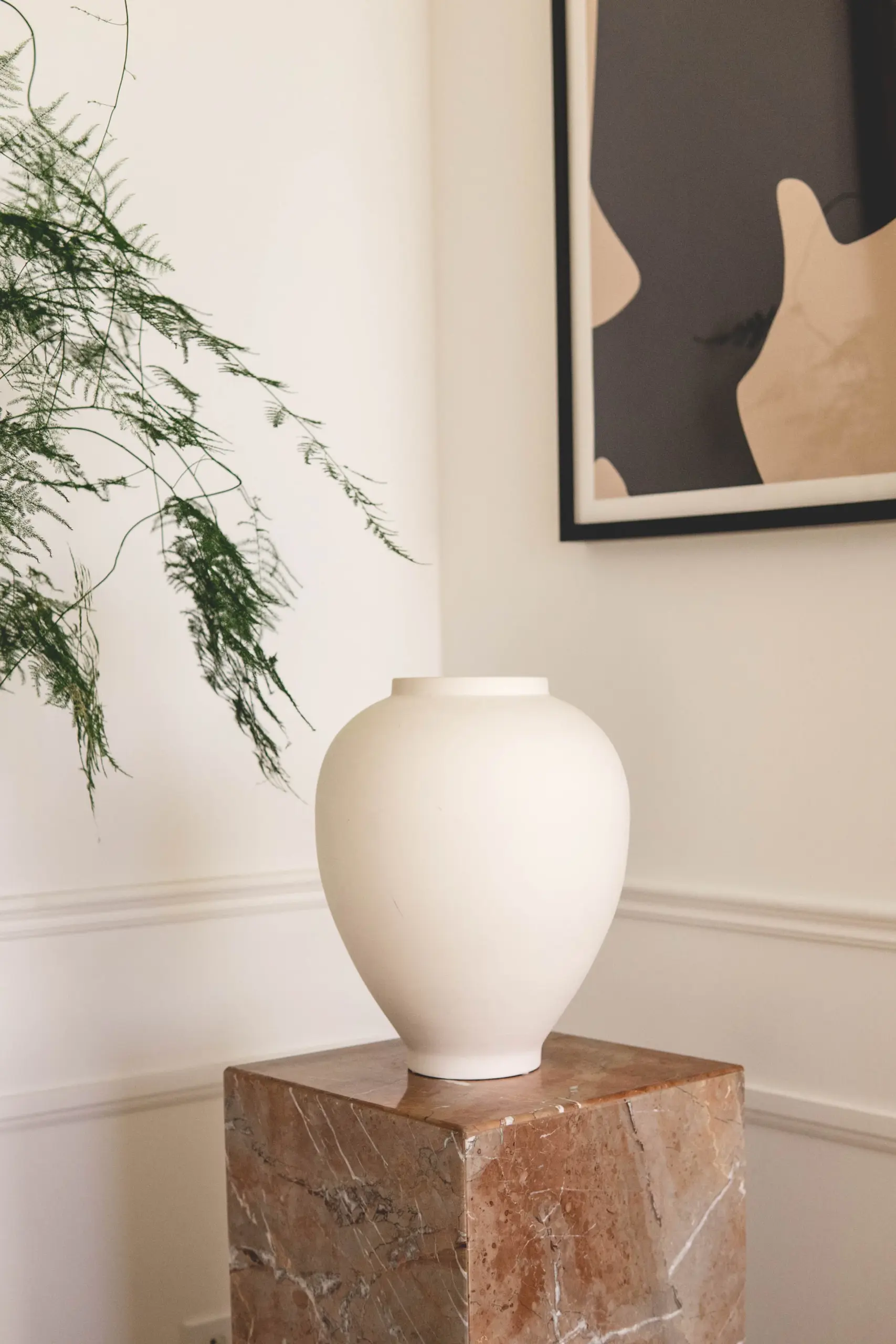 Round white ceramic vase on a pink marble block