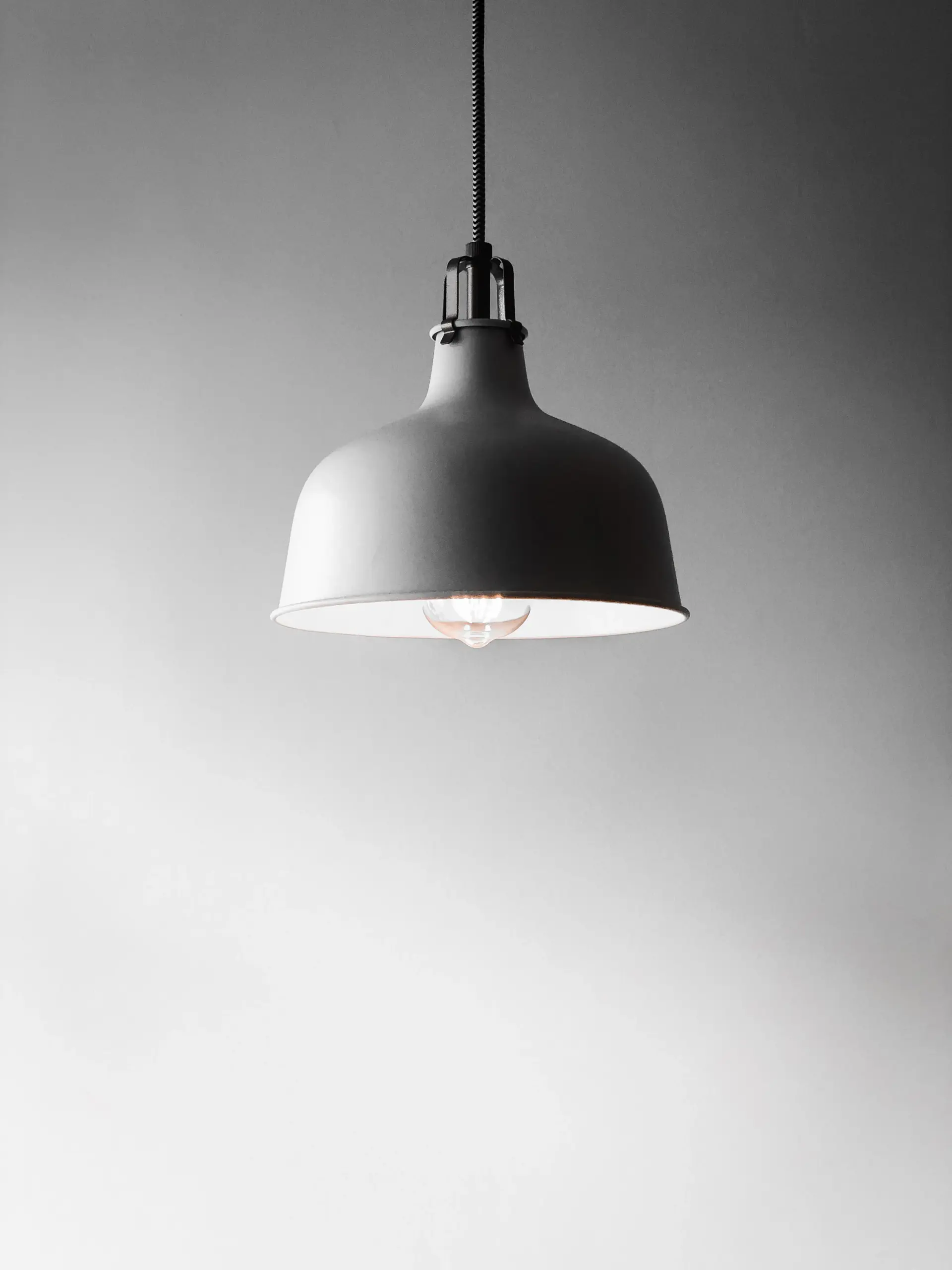 Matte grey metal dome pendant lamp hanging against a pale wall