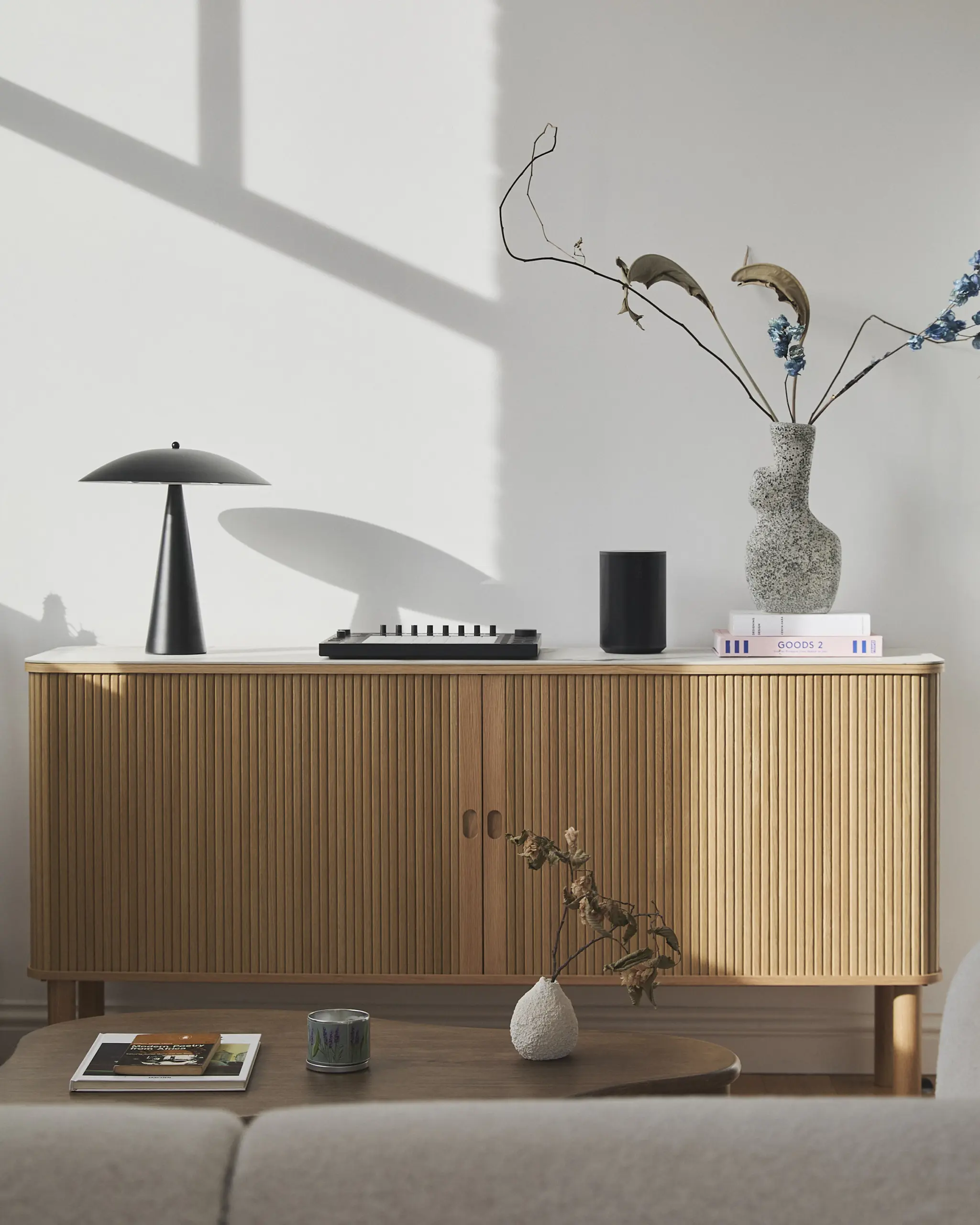 Fluted oak sideboard with a black table lamp and vases on top