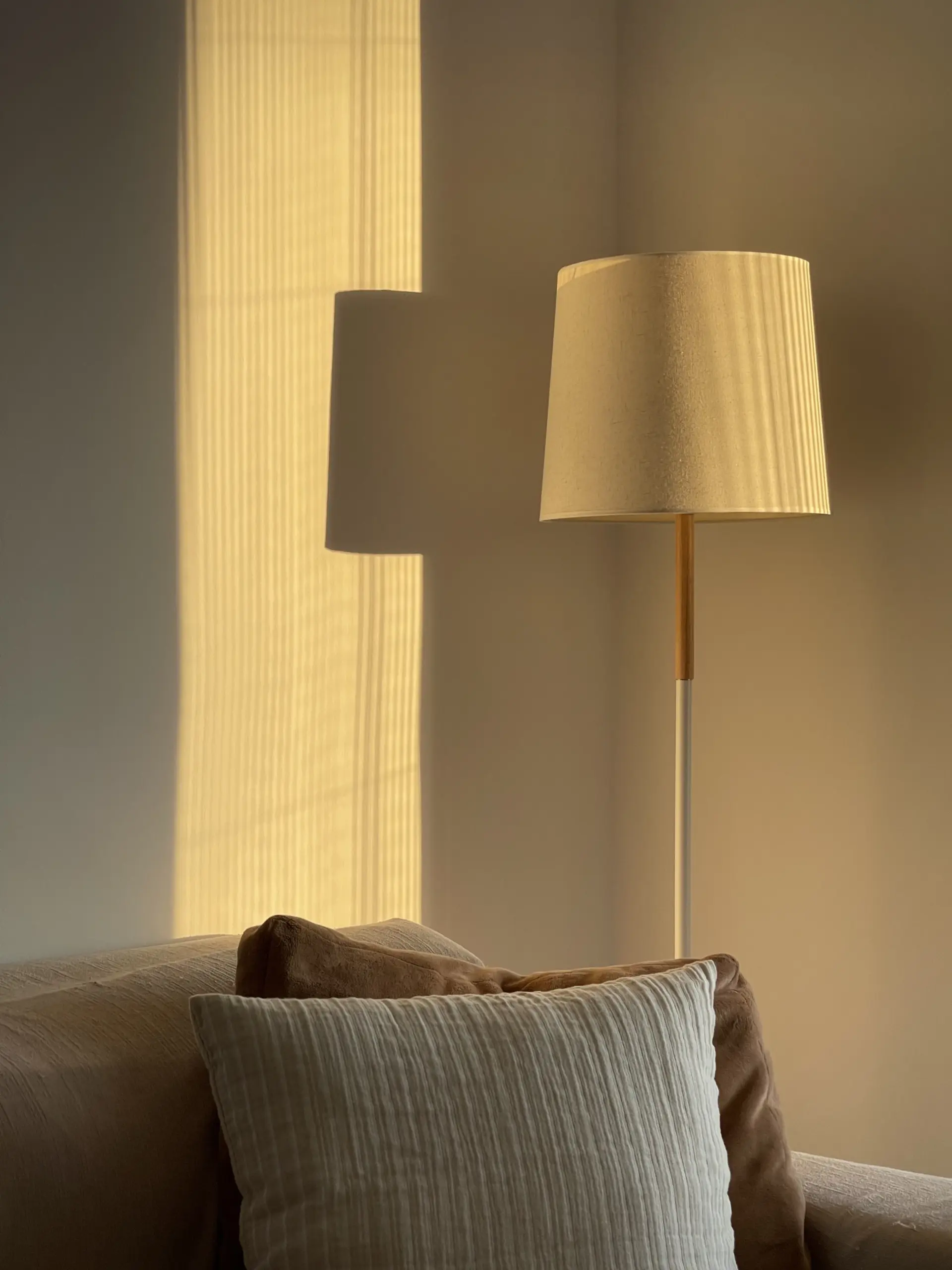 Floor lamp with a pleated linen shade glowing in a warm corner