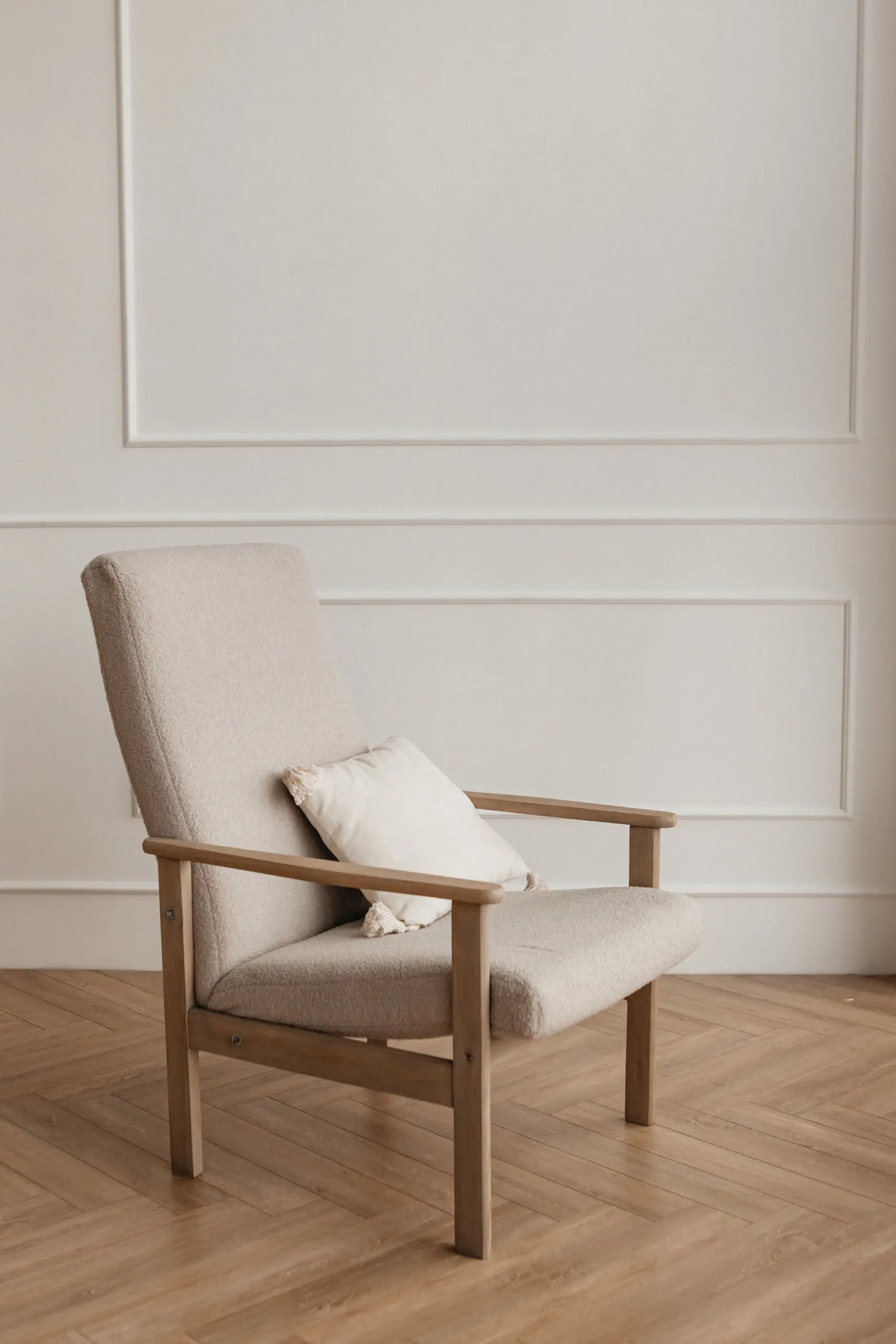 Oak frame armchair with cream seat and back cushions on a wooden floor